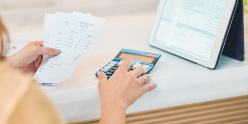 woman using a digital tablet and calculator while going through paperwork