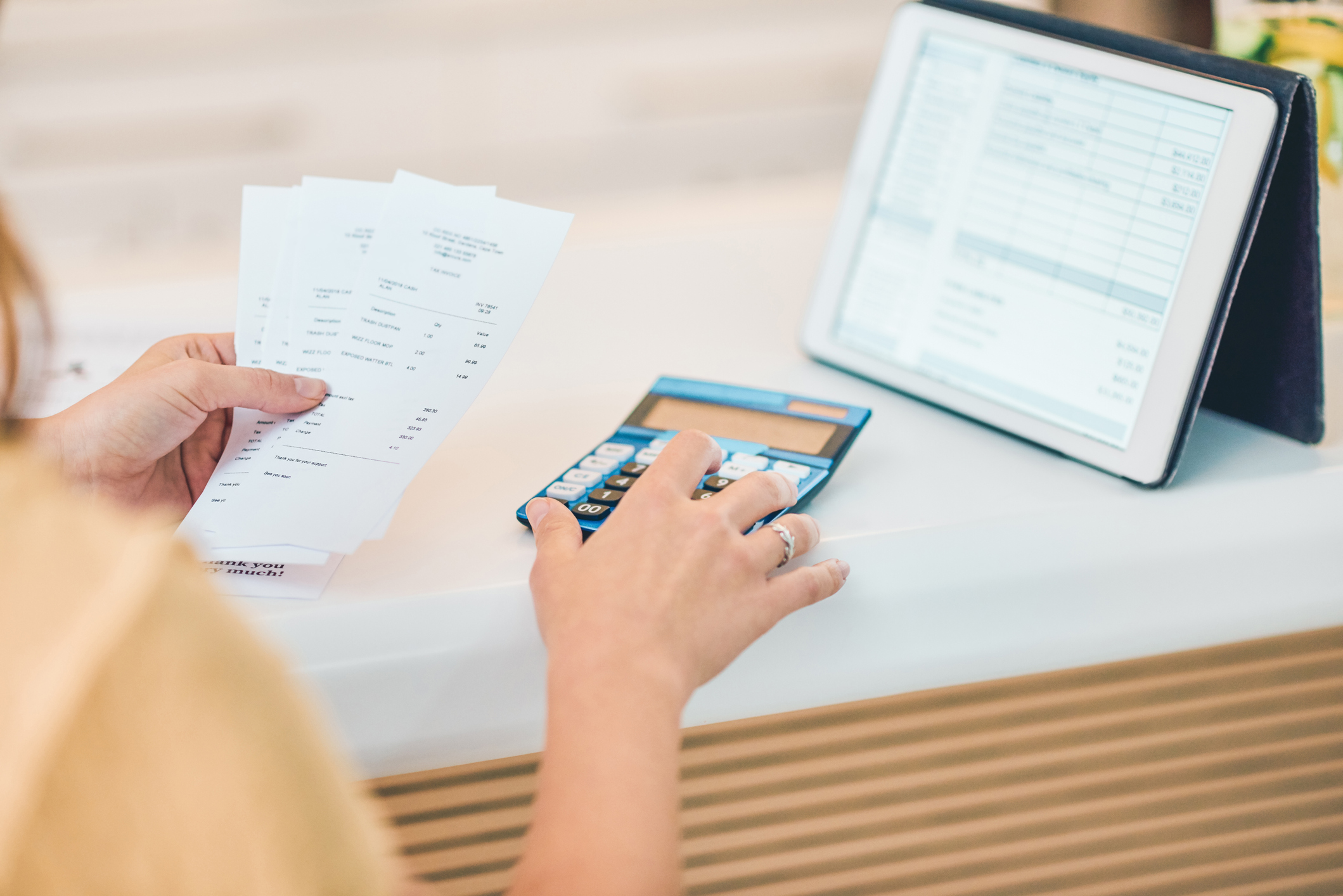 woman using a digital tablet and calculator while going through paperwork